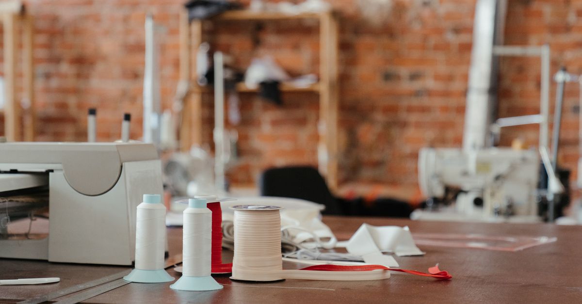 Mesa de trabajo con pliegos de papel, hilo y herramientas de encuadernación